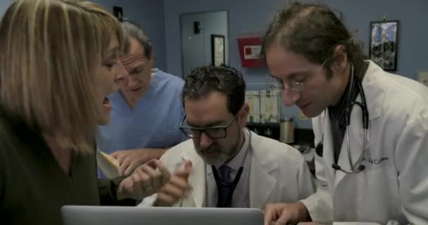 Dottore fuori di testa mentre multitasking quando altre tre persone parlano con lui — Video Stock