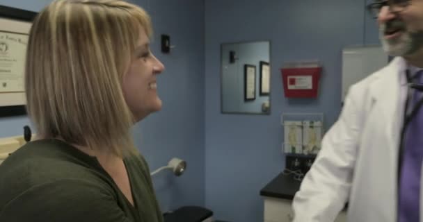 Ο γιατρός χαιρετά μια γυναίκα ασθενή σε ένα εξεταστήριο κατά τη διάρκεια μιας επίσκεψης στο ιατρικό γραφείο — Αρχείο Βίντεο