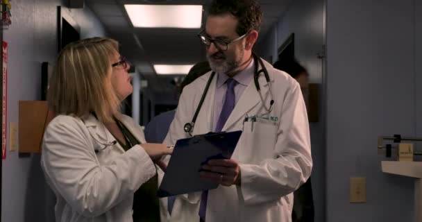 Doctors consulting on a case while a medical assistant checks in another patient — Stock Video