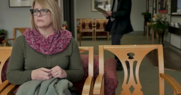 Donna seduta in una sala d'attesa inizia ad ascoltare un medico che la conforta — Video Stock