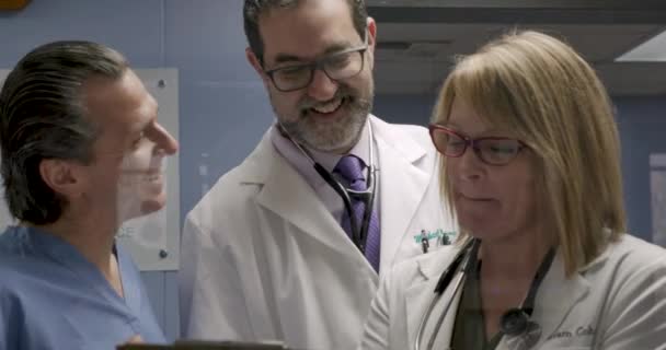 Tres sonrientes profesionales médicos felices trabajando en un caso juntos — Vídeo de stock