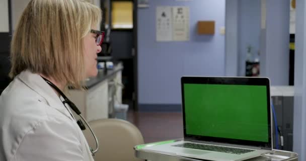 Kobieta lekarz wideo rozmowy do zielonego ekranu komputera w praktyce medycznej — Wideo stockowe