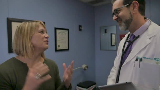 Paciente mujer discutiendo su historia clínica con su médico varón — Vídeo de stock