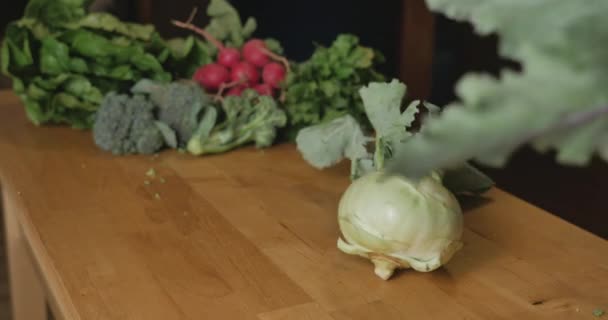 Hand putting a white and purple kohlrabi vegetable on a wooden cutting board — Stock Video