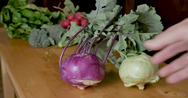Hand aanraken van een paarse koolrabi groente op een houten snijplank — Stockvideo