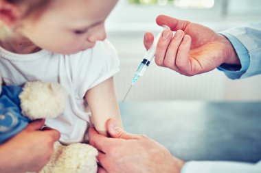 Doktor Pediyatrist tatlı bir kıza aşı enjekte ediyor.