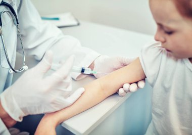 Doktor Pediyatrist tatlı bir kıza aşı enjekte ediyor.