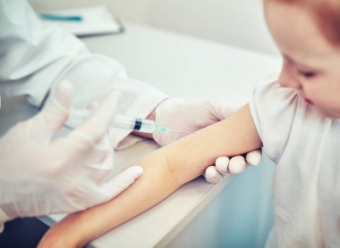 Doktor Pediyatrist tatlı bir kıza aşı enjekte ediyor.