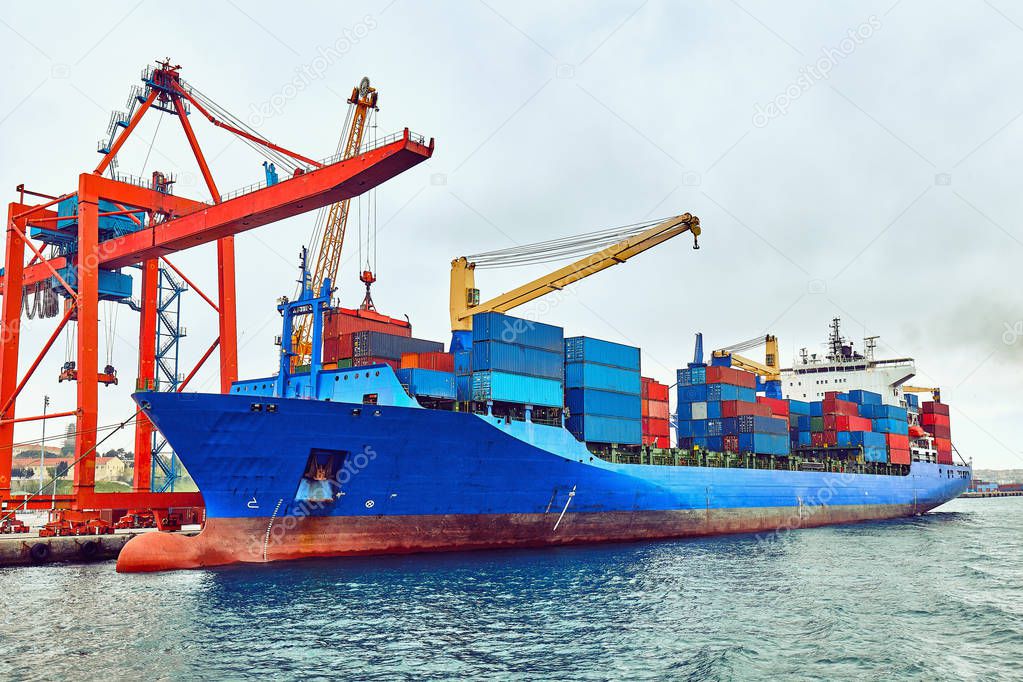 Container Cargo freight ship with working crane loading bridge