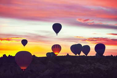 Balonlar gökyüzünde kayalıkların üstünde.