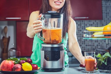 Kadın mutfak yeşil smoothie yapmak. Blender üzerinde odaklanmak.