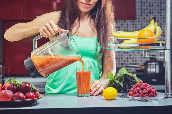 Woman making green smoothie on the kitchen. Focus on the blender.
