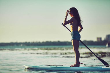 Çekici genç kadın sörf küreği kadar ayağa