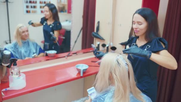 プロの美容師が彼女のクライアントの髪を染める — ストック動画