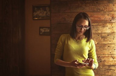 Sevimli gülümseme cep telefonu kullanarak modern café Ardiles siting ile neşeli genç kız öğrenci