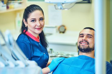 Diş muayenehanesinde gülümseyen ve tatmin olmuş bir hasta.