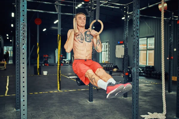 Sportsman doing muscle ups exercise on the gymnastic rings.