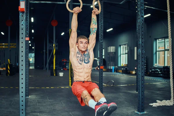 Sportsman doing muscle ups exercise on the gymnastic rings.