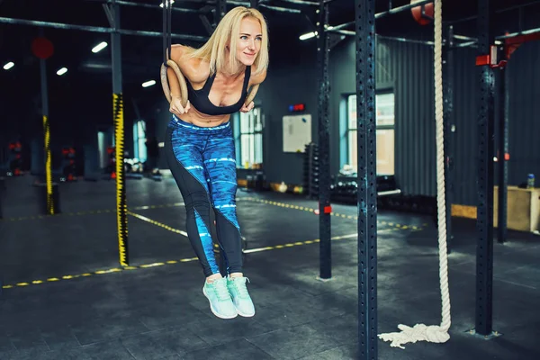 Sporty woman exercising with gymnastic rings at gym