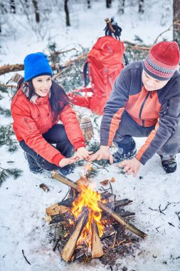 Mutlu çift bir kamp ateşi karlı kış orman üzerinde
