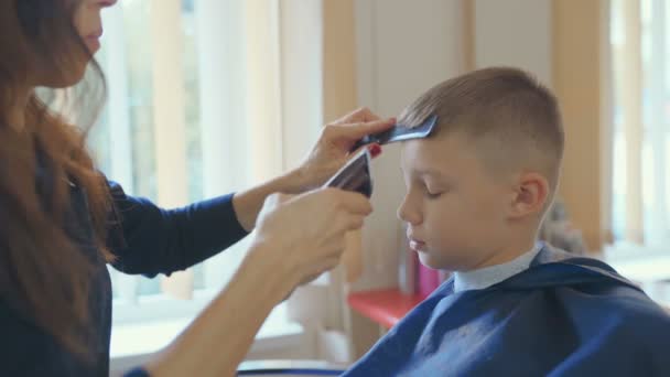Hairdresser cutting hair with barber scissors in children hairdressing salon. — Stock Footage Hairdresser Cutting Hair Barber Scissors Children Hairdressing Salon Video Clip