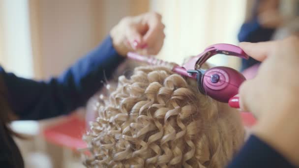 微笑的女理发师做发型漂亮的年轻女子与长的金发在美发沙龙 — 图库视频影像