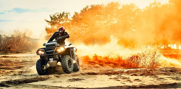 Teen riding ATV in sand dunes making a turn in the sand Stock Picture