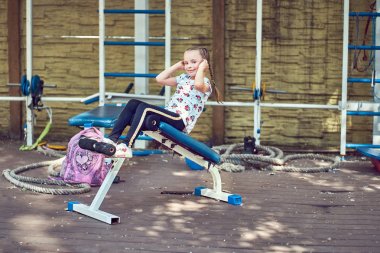 Neşeli çocuk spor ekipmanları üzerinde egzersiz yapıyor.