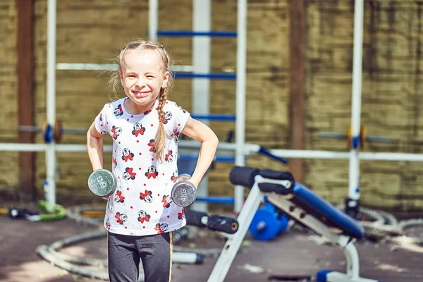 Vrolijk kind doet oefeningen op sportuitrusting. — Stockfoto