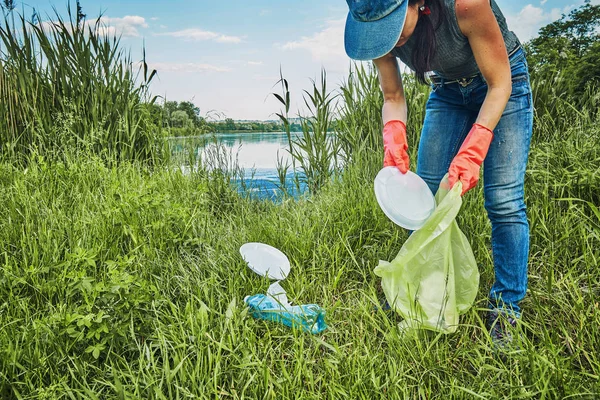 Genç kız çöpü toplayıp çöpe atıyor.
