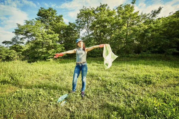 Jovencita recogiendo la basura y poniéndola en una basura b — Foto de Stock