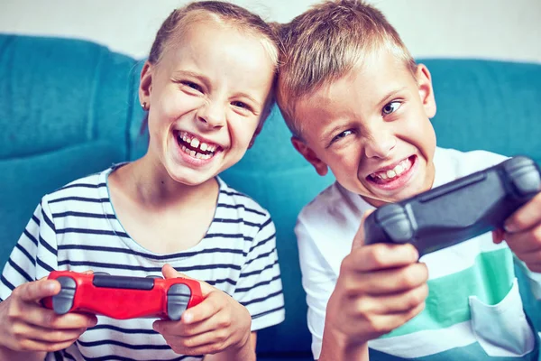 Anak-anak secara emosional bermain video game sambil duduk di atas couc — Stok Foto