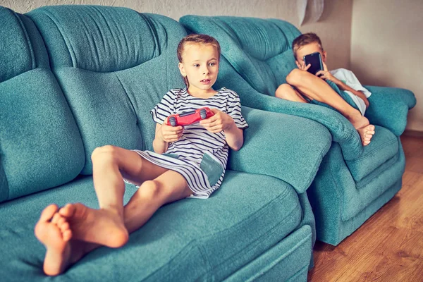 Los niños juegan emocionalmente a un videojuego mientras están sentados en el couc — Foto de Stock