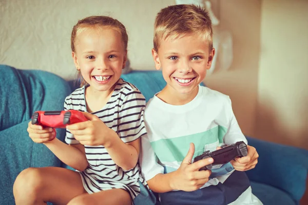 Дети эмоционально играют в видеоигру, сидя на кубе — стоковое фото