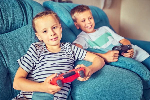 Anak-anak secara emosional bermain video game sambil duduk di atas couc — Stok Foto