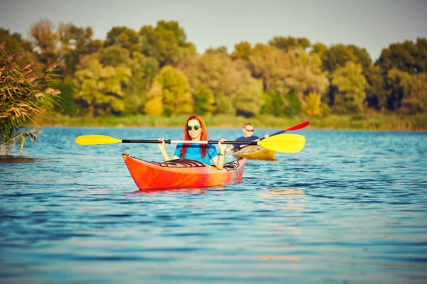 La gente kayak durante la puesta del sol en el fondo. Diviértete en tu f — Foto de Stock