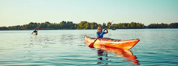 Les gens kayak pendant le coucher du soleil en arrière-plan. Amusez-vous dans votre f — Photo