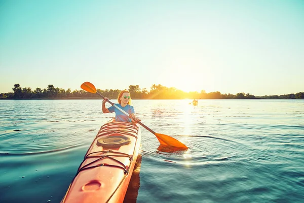 Les gens kayak pendant le coucher du soleil en arrière-plan. Amusez-vous dans votre f — Photo