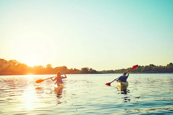 Les gens kayak pendant le coucher du soleil en arrière-plan. Amusez-vous dans votre f — Photo