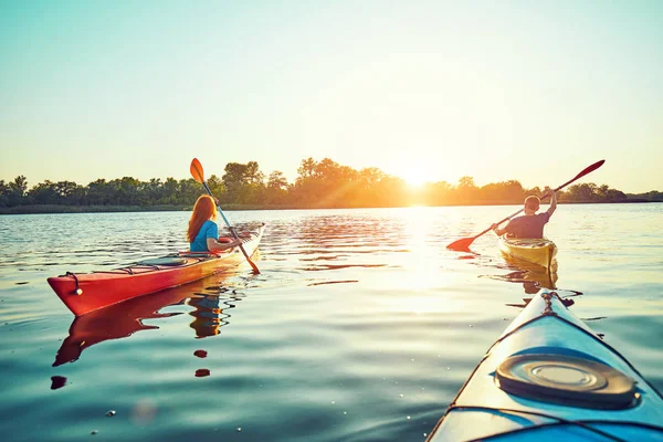 La gente kayak durante la puesta del sol en el fondo. Diviértete en tu f —  Fotos de Stock