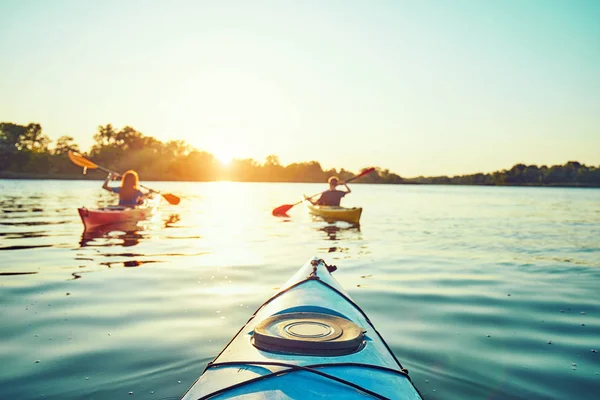 La gente kayak durante la puesta del sol en el fondo. Diviértete en tu f —  Fotos de Stock