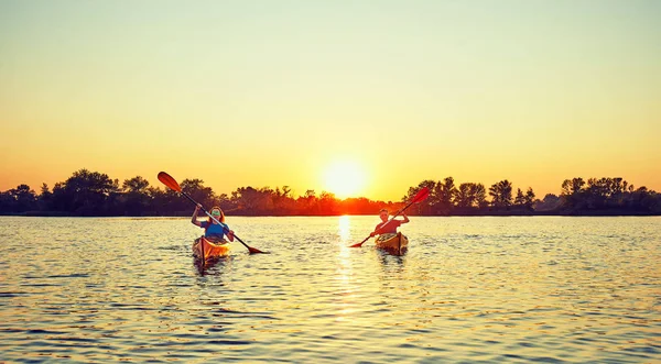 Mensen kajakken tijdens zonsondergang op de achtergrond. Veel plezier in uw f — Stockfoto