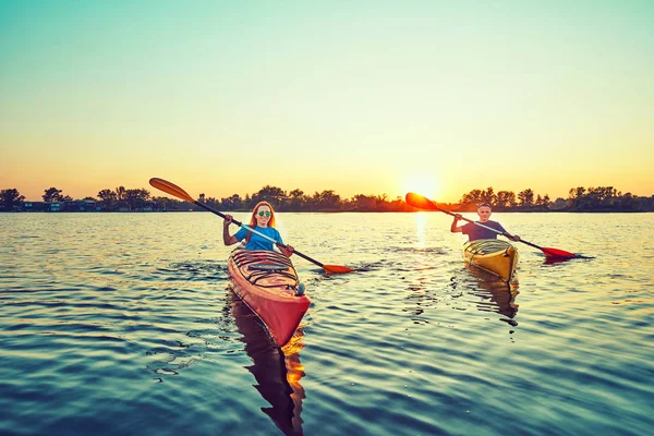 Les gens kayak pendant le coucher du soleil en arrière-plan. Amusez-vous dans votre f — Photo