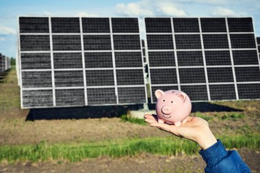 Arka planda fotovoltaik güneş enerjisi panelleri olan el ele tutuşma para banknotu, 