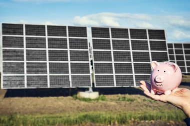 Arka planda fotovoltaik güneş enerjisi panelleri olan el ele tutuşma para banknotu, 
