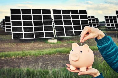 Arka planda fotovoltaik güneş enerjisi panelleri olan el ele tutuşma para banknotu, 