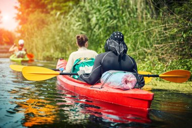 Bir grup genç kanoyla nehirde rafting yapıyor.