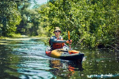 Bir grup genç kanoyla nehirde rafting yapıyor.