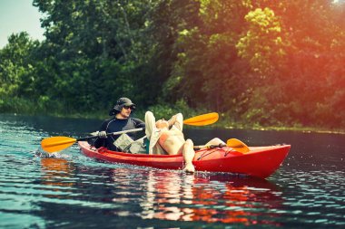 Bir grup genç kanoyla nehirde rafting yapıyor.