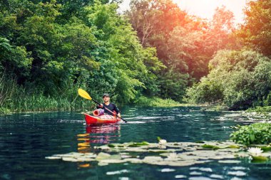 Bir grup genç kanoyla nehirde rafting yapıyor.